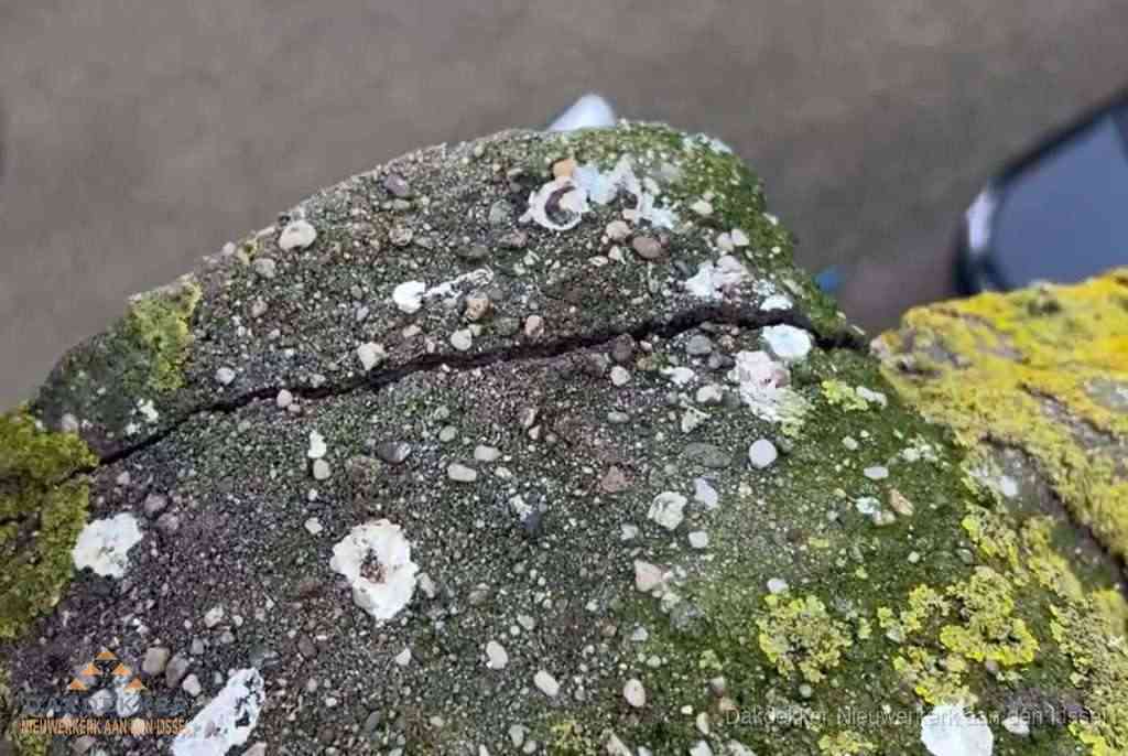 Beschadigde en verweerde nokvorst met scheuren en mos in Nieuwerkerk aan den IJssel